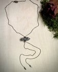 Tourmalinated Quartz Charm on an oxidized bolo chain that hangs at approximately 15 inches. Displayed with greenery.